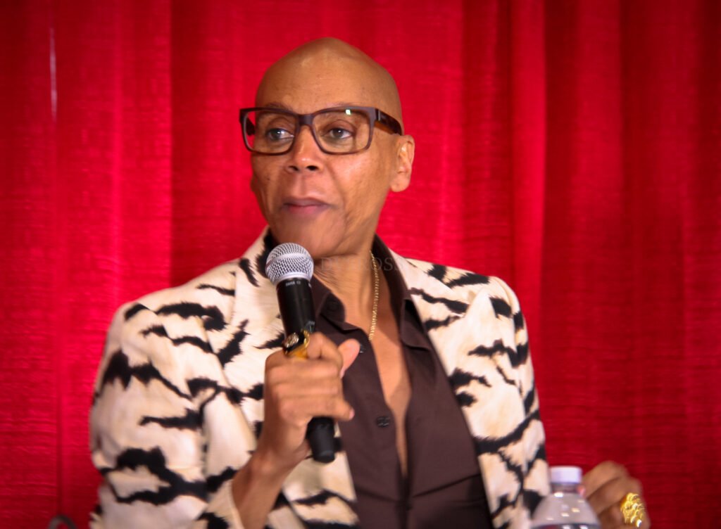 Photo of RuPaul out of drag speaking in a microphone