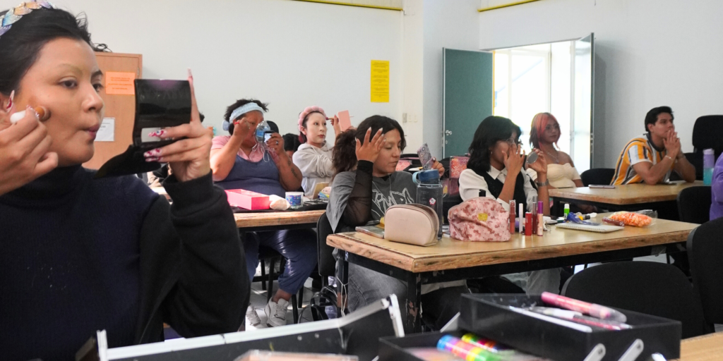 Photo of students applying makeup in drag makeup class