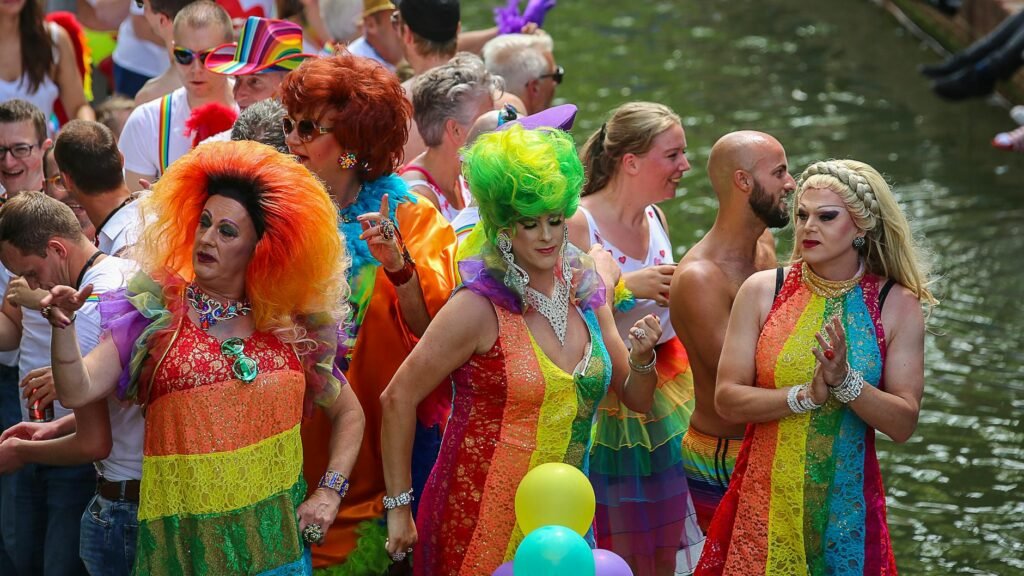 three people wearing rainbow dresses dancing in front of crowd